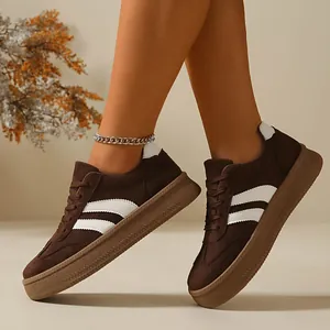 Side view of women's brown suede German trainers with white stripes and flat rubber sole