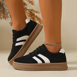 Close-up of retro black suede sneakers with thick brown gum soles worn by a model