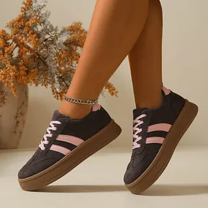 Close-up detail of dark grey German army trainer sneakers featuring pink stripes and gum sole