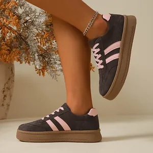 Detail view of women's vintage dark grey suede sneakers with pink stripes and gum soles.