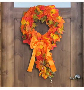 Vibrant autumn maple leaf wreath with large orange bow hanging on a rustic wooden door