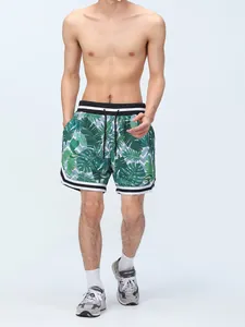 Detailed view of men's green tropical leaf print mesh sports shorts with lining on model