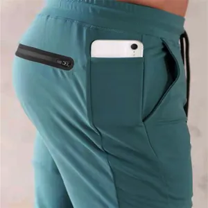 Close-up detail of teal sports sweatpants with a dedicated smartphone pocket for gym