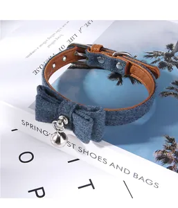 Macro view of blue felt pet collar with elegant bow tie and silver bell accessory