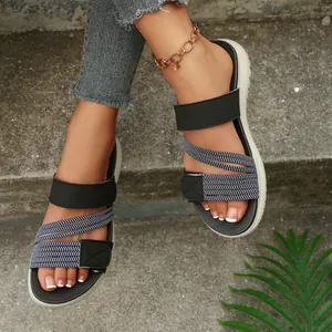 Detalle de sandalias negras casuales con tiras elásticas y cierre de velcro ajustable.