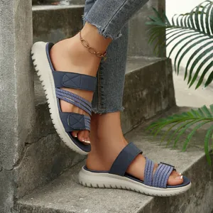 Sandalias playeras planas para mujer en azul marino con tiras elásticas y velcro.