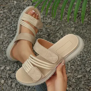 Vista detallada de sandalias beige para mujer con correas de velcro y cordones elásticos.