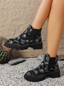 Detalle de botines Chelsea negros para mujer con estampado de mariposas y suela gruesa