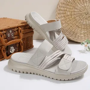 Detalle de sandalias de cuña beige para mujer con correas y suela dentada gruesa.