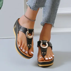 Detalle de primer plano de sandalias de cuña negras para mujer con adornos dorados