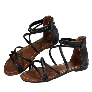 Elegant black flat Roman sandals with cross straps and rear zipper on white background.