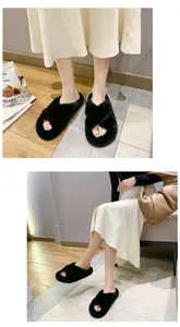 Détail de pantoufles en fausse fourrure noire à brides croisées portées par un modèle.