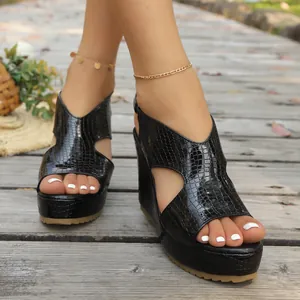 Detailopname van zwarte sleehaksandalen met krokodillenprint en peep-toe
