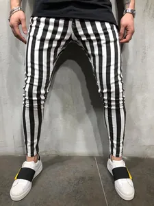 Detailed view of men's black and white vertical striped skinny trousers on model