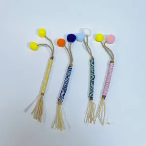 Detailed macro view showing natural silvervine sticks with colorful yarn and soft pom-poms
