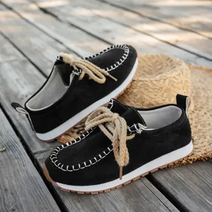 Detail view of black suede loafers with thick rope laces and white contrast stitching
