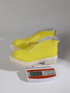 Detail showing the weight of bright yellow platform ankle boots on a digital scale.
