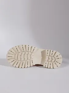 Close-up macro view of a cream chunky lug boot sole featuring deep traction tread.