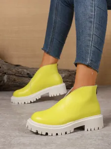 Detail view of neon yellow chunky platform ankle boots with back zipper closure.