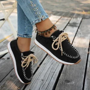 Detail view of black suede ethnic style loafers with thick rope laces on wooden deck.