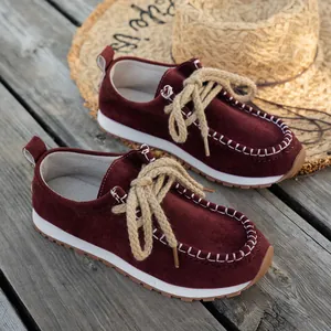 Detail of burgundy suede loafers featuring thick rope laces and ethnic stitching