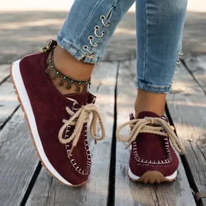 Close-up of burgundy suede ethnic loafers with white stitching and rope laces