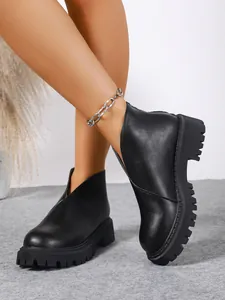 Close-up detail of black chunky platform boots with V-cut and back zipper closure