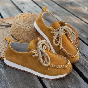 Close-up of yellow suede loafers with thick rope laces and moccasin stitching