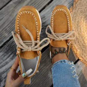Close-up of mustard yellow suede loafers with thick rope laces and stitching detail