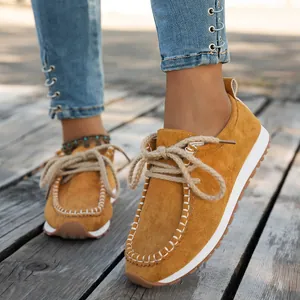 Close-up of mustard yellow suede loafers with thick rope laces and white stitching