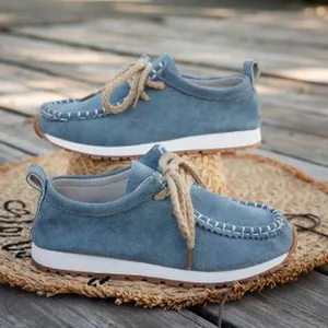 Close-up detail of blue suede moccasins with rustic hemp laces on a woven mat