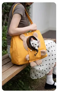 Détail d'un sac de transport pour animaux en toile jaune en forme d'ours avec chaton