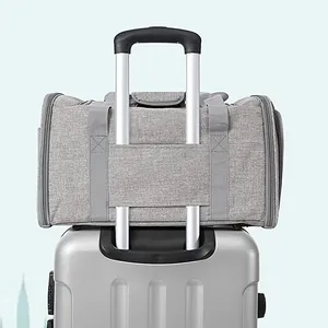Grey breathable foldable pet carrier bag secured to a silver suitcase telescopic handle