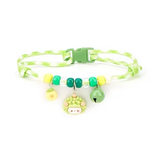 Detail view of a green checkered pet collar with a cute cartoon sheep pendant and bell