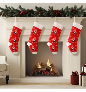 Set of four red knitted Christmas stockings with gnome patterns hanging on white fireplace