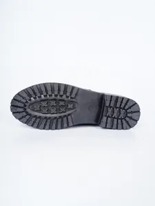 Detailaufnahme der rutschfesten Gummisohle einer schwarzen Retro-Stiefelette im britischen Stil.