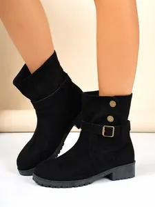 Nahaufnahme von schwarzen Wildleder-Stiefeletten mit Seitenschnalle und Zierknöpfen
