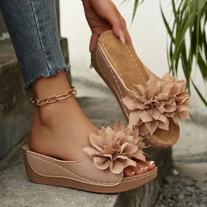 Detalle de elegantes sandalias de cuña con una gran flor de tela de varias capas.
