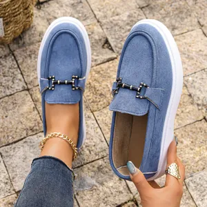 Primo piano di mocassini platform in camoscio blu con fibbia in metallo e suola bianca