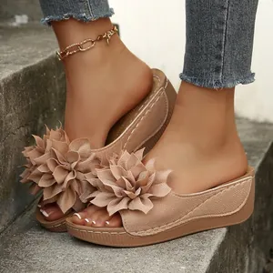 Primer plano de sandalias de cuña beige con decoración floral de gran tamaño en los pies