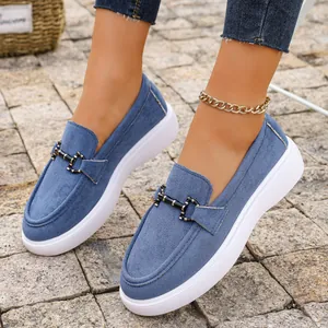 Primo piano di eleganti mocassini in denim blu con fibbia in metallo e suola platform