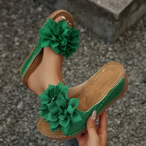Primer plano de sandalias de plataforma verdes decoradas con grandes flores de tela.