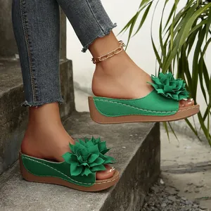 Vista lateral de sandalias con cuña verdes decoradas con una gran flor de tela 3D