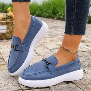 Dettaglio dei mocassini in denim blu da donna con elegante fibbia in metallo decorativa
