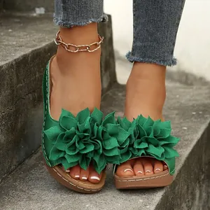 Sandalias planas verdes elegantes con flores de tela decorativas y suelas cosidas.