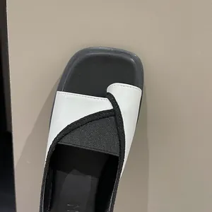 Macro detail of black and white square toe thong sandals featuring premium leather texture.