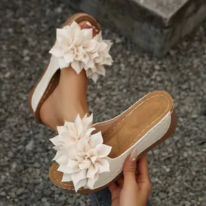 Vista detallada de sandalias con cuña beige con flores 3D y suela pespunteada
