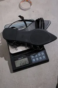 Detail showing weight of black pointed-toe flat sandal on electronic scale, 203.4g