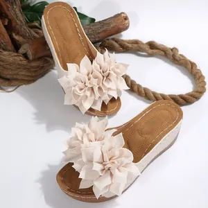 Detalle de elegantes sandalias con cuña con flores beige de gran tamaño en las tiras.