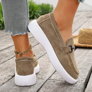 Dettaglio di mocassini in camoscio marrone con suola platform bianca e fibbia metallo